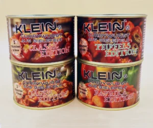 Vier Dosen Klein’s Currywurst aus Bielefeld im klassischen Probierpaket: Classic Edition, Teufels Edition, Jäger Edition und Paprika Edition – handgemachte Currywürste mit verschiedenen Geschmacksrichtungen aus traditioneller Herstellung.